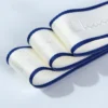 Close-up shot of a roll of custom jacquard woven webbing tape with a raised brand logo, showing detailed stitching and premium fabric texture.
