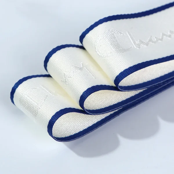 Close-up shot of a roll of custom jacquard woven webbing tape with a raised brand logo, showing detailed stitching and premium fabric texture.