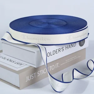 A flat lay of customized woven brand logo Jacquard Webbing Tape in various colors and widths, displayed on books.