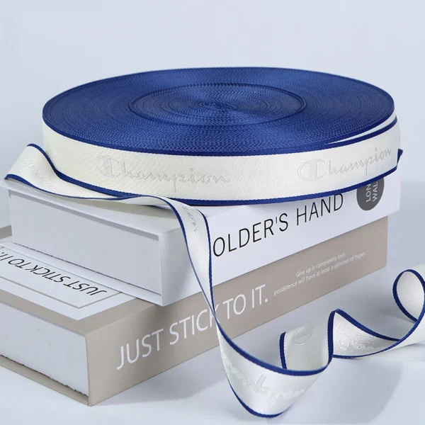 A flat lay of customized woven brand logo Jacquard Webbing Tape in various colors and widths, displayed on books.