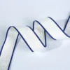 Macro photograph showing the high-density woven logo detail and durable edge finish of a custom apparel trim tape.