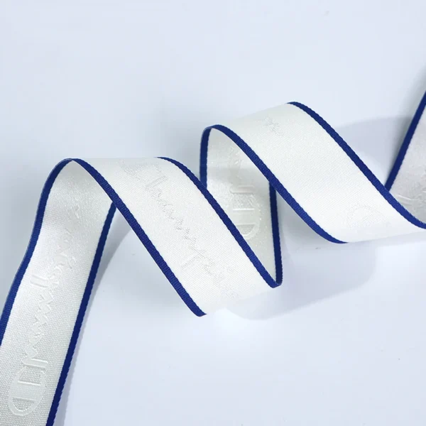 Macro photograph showing the high-density woven logo detail and durable edge finish of a custom apparel trim tape.