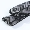 Macro close-up of custom jacquard elastic webbing tape showing intricate black and white athletic woven patterns and soft fabric texture, designed for apparel waistbands.