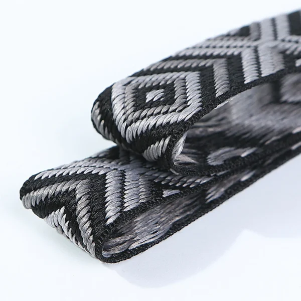 Macro close-up of custom jacquard elastic webbing tape showing intricate black and white athletic woven patterns and soft fabric texture, designed for apparel waistbands.