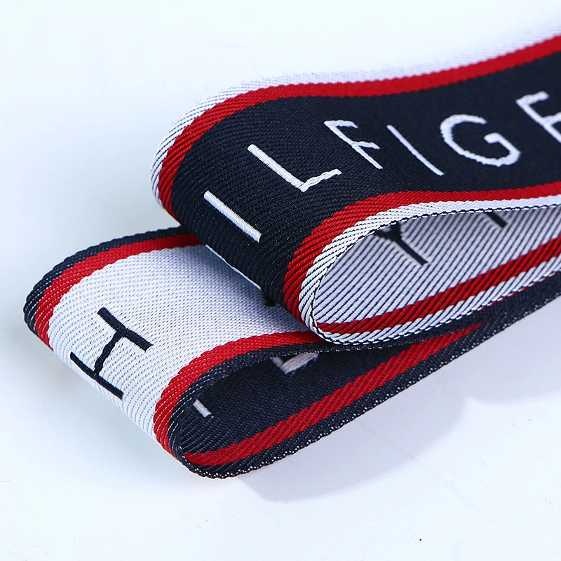 Macro photograph showcasing the double-sided pattern weave and clean edge stitching on a high-density jacquard ribbon tape.